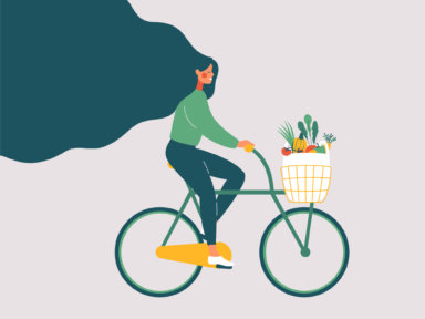 Young smiling girl with long hair riding bicycle with fresh vegetables in front basket.