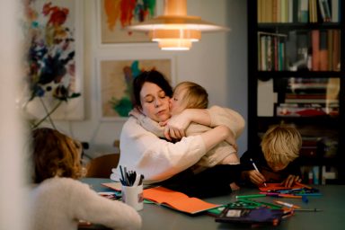 Mother embracing girl with down syndrome while sitting by dining table at home